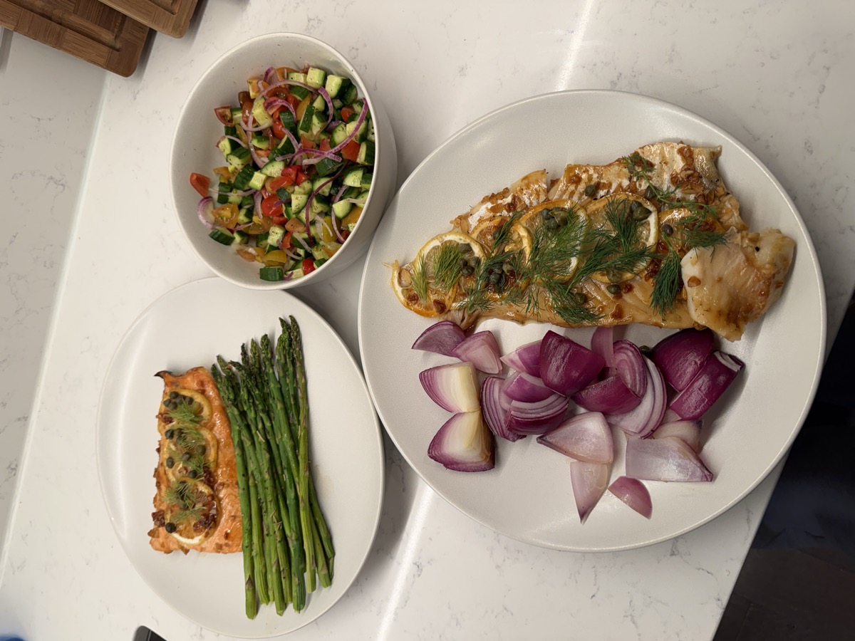 Plated lemon herb salmon with asparagus, roasted red onions, and fresh cucumber salad