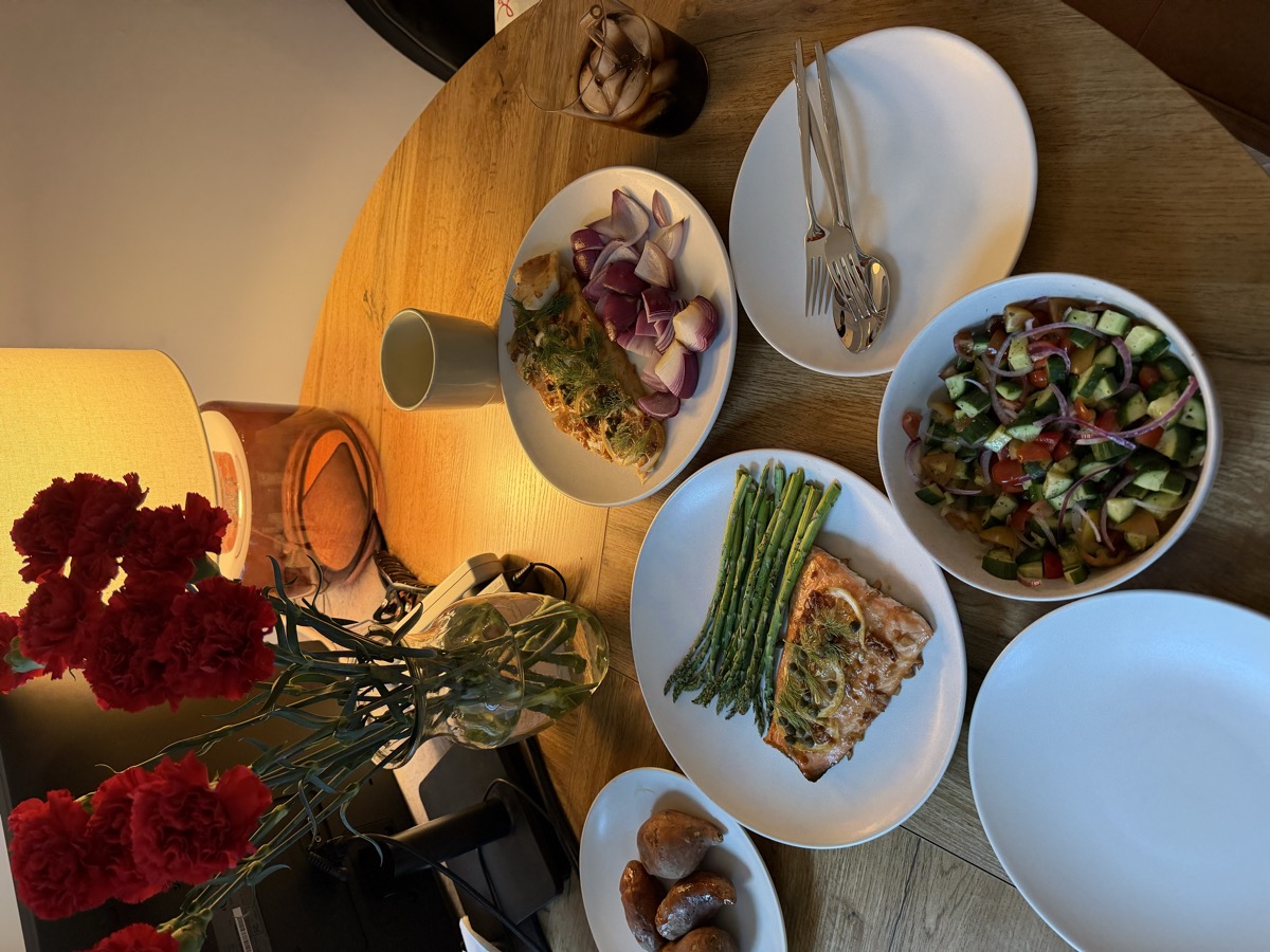 Dinner table spread with salmon, asparagus, salad, and red carnations