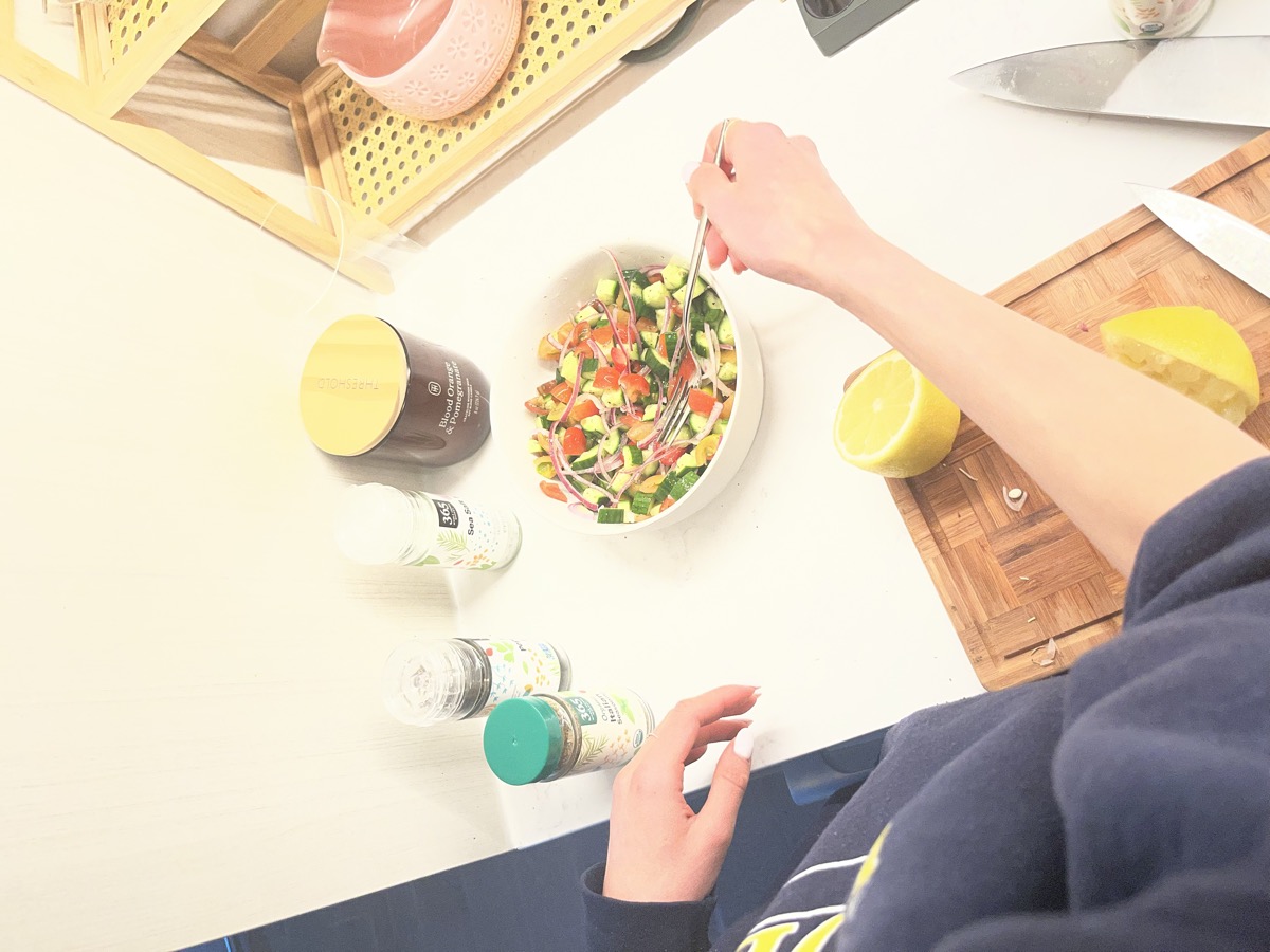 Mixing the fresh cucumber, tomato, and avocado salad with seasonings